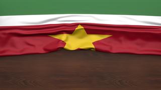 수리남 국기, 반이 접혀진채 나무 책상 위에 놓인 국기