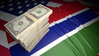 Gambia National Flag, American dollars and flag placed on top of the American flag