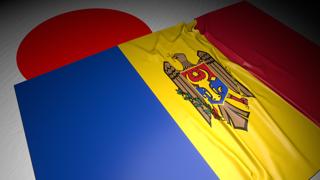Moldova National Flag, The national flag placed on top of the Japanese flag on a desk in a dark space