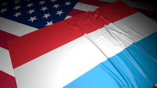룩셈부르크 국기, 어두운 공간속 책상위 미국 국기위에 놓인 국기