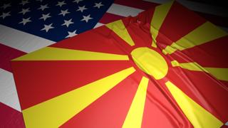 북마케도니아 국기, 어두운 공간속 책상위 미국 국기위에 놓인 국기