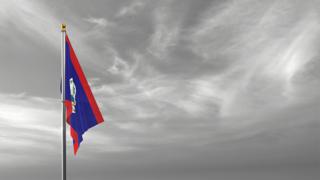 Belize National Flag, The national flag and flagpole visible from afar against a black and white sky background