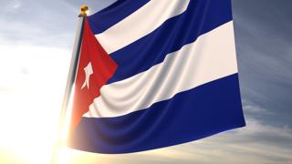 쿠바 국기, 어두운 파란색 하늘을 배경으로 가까이에서 보이는 펄럭이는 국기와 국기봉