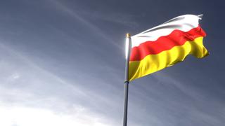 남오세티아 국기, 어두은 파란 하늘을 배경으로 위로 올려다보이는 국기와 국기봉